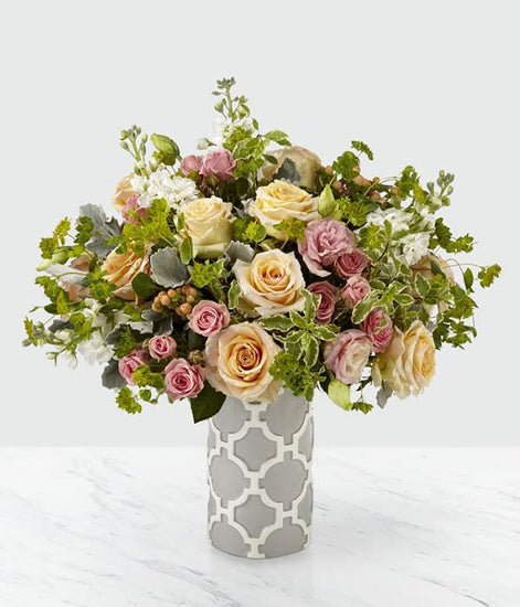 With an artful design of peach and pink roses, and complements of white lisianthus, this bouquet bursts with refined elegance.
