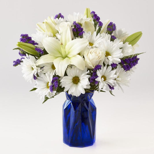 Beautiful bouquet of lilies, roses and statice. Our Beyond Blue Bouquet features a deep blue vase and a gorgeous array of white and purple blooms.