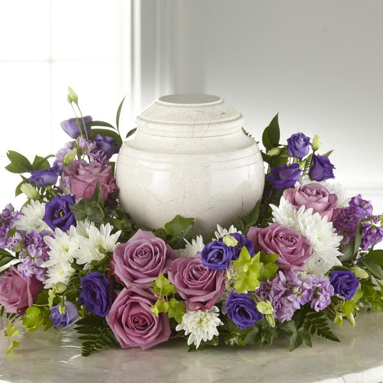 purple blooms of lisianthus, roses, stock and white cushion pompons.   Adornment is approximately 11"H x 23"W  ***Urn show is not included.***